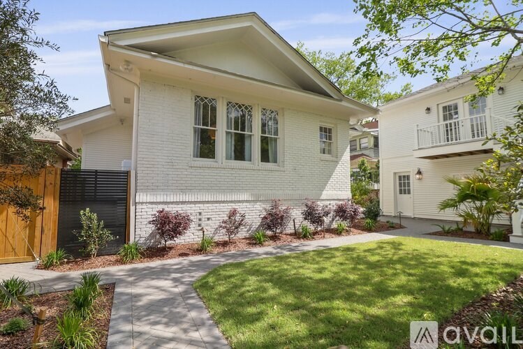 A white house with a black gate and a small garden in front.
