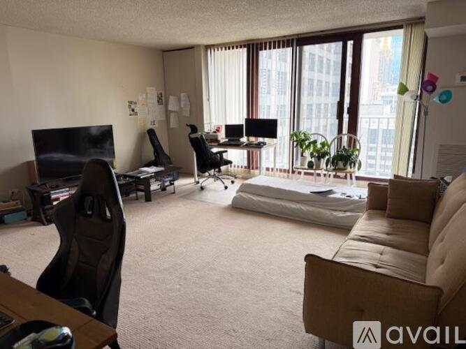 A living room with a couch, a chair, a desk, and a TV.