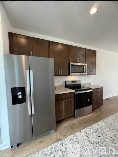 A modern kitchen with a stainless steel refrigerator and wooden cabinets.