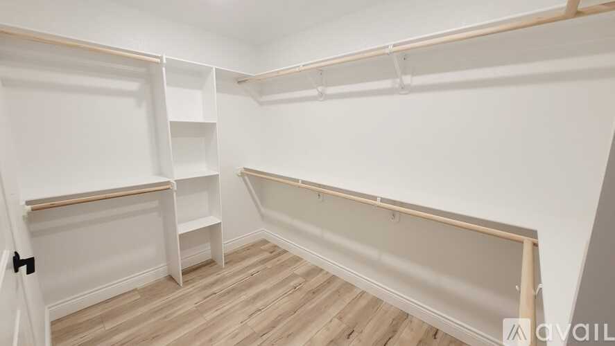 A room with white walls and wooden flooring, featuring built-in shelving.