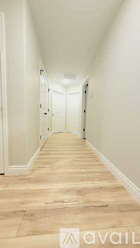 A long hallway with wood floors and white walls.