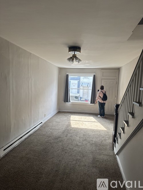 A person is standing in a room with a window and a staircase.