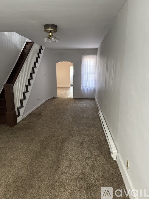 A long hallway with a staircase on the left and a door at the end.