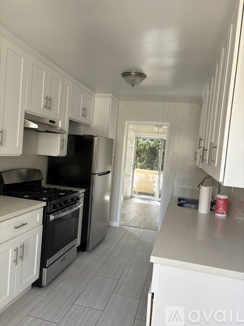 A kitchen with white cabinets and a black refrigerator.