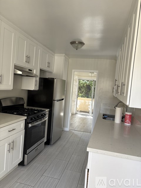A kitchen with white cabinets and a black refrigerator.