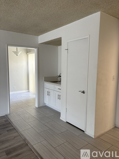 A kitchen area with white cabinets and a door leading to another room.