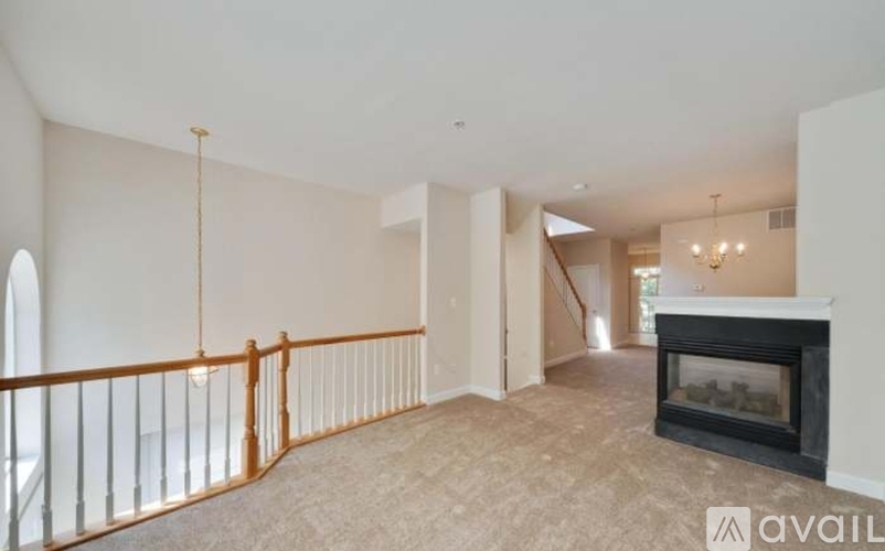 A living room with a fireplace and a balcony with a railing.