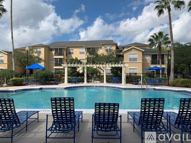 A pool area with chairs and a building in the background.