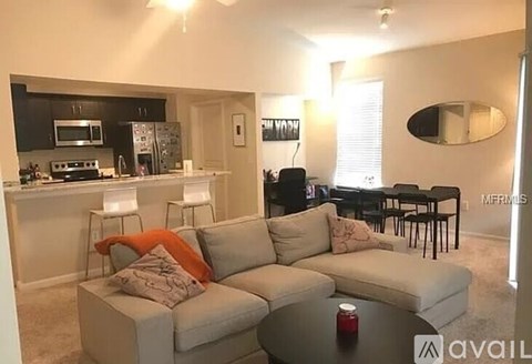 A living room with a grey couch and a black dining table.