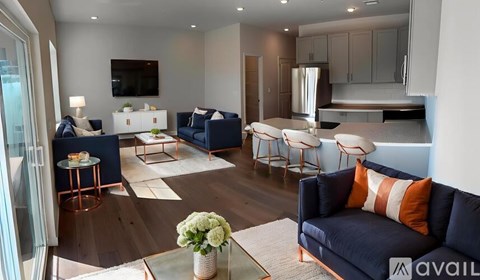 A living room with a dark blue sofa and a glass table with a vase of flowers on it.
