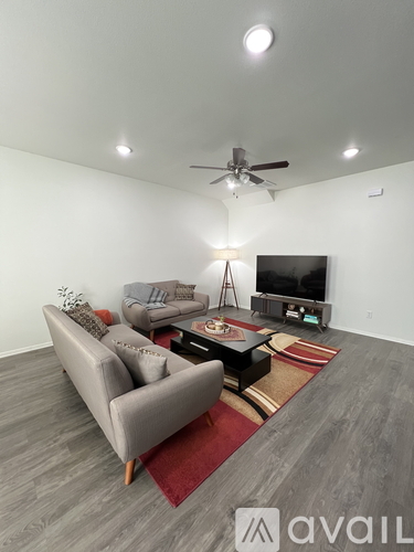 A living room with a grey couch, a red rug, and a television.