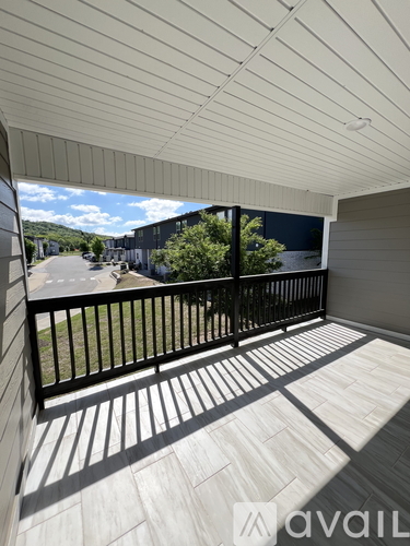 A balcony with a black railing and a view of a street and buildings.