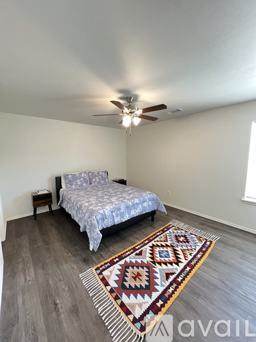 A bedroom with a bed, a rug, and a ceiling fan.