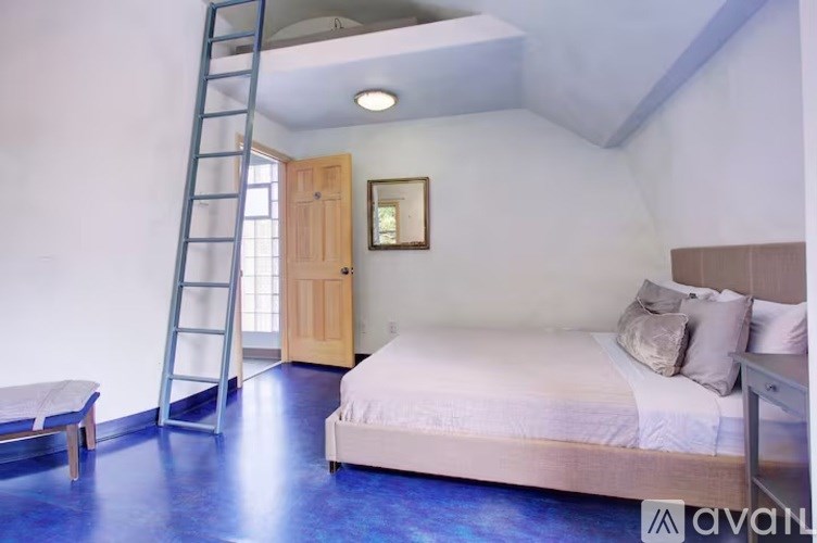 A bedroom with a bed, a bench, and a ladder.
