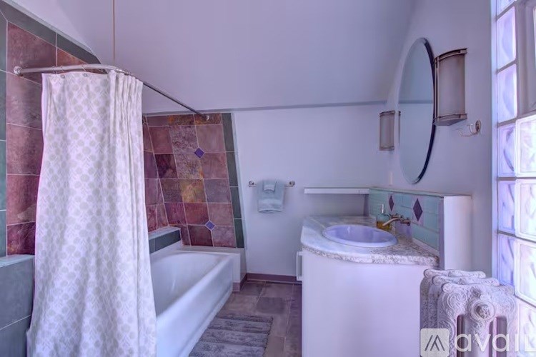 A bathroom with a white tub, sink, and shower curtain.