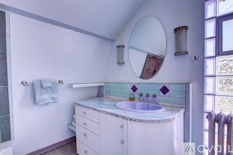 A bathroom with a white sink and a round mirror.