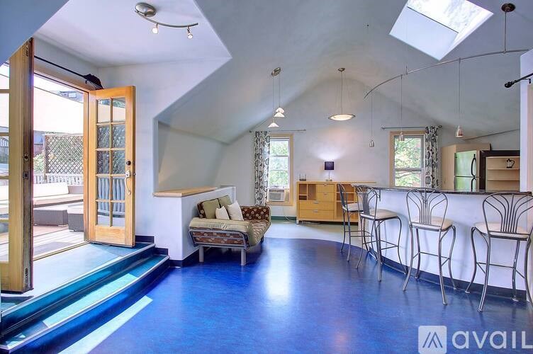 A living room with a blue floor and a skylight.