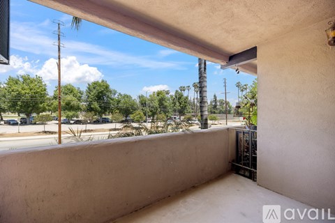 A balcony with a view of a street and trees.
