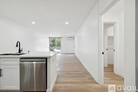 A kitchen with a stainless steel dishwasher and wooden flooring.