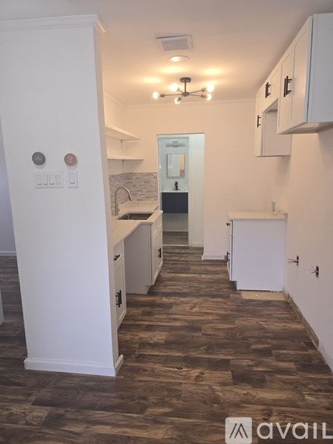 A kitchen with white cabinets and a wooden floor.