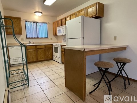 A kitchen with white appliances and wooden cabinets.