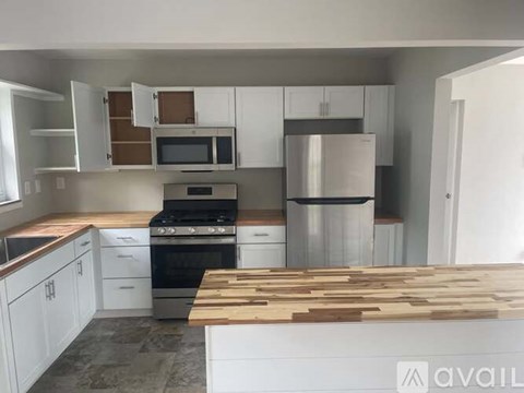 A kitchen with white cabinets and a wooden cutting board on the counter.