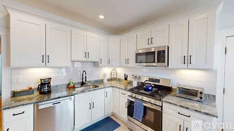 A kitchen with white cabinets and granite countertops.