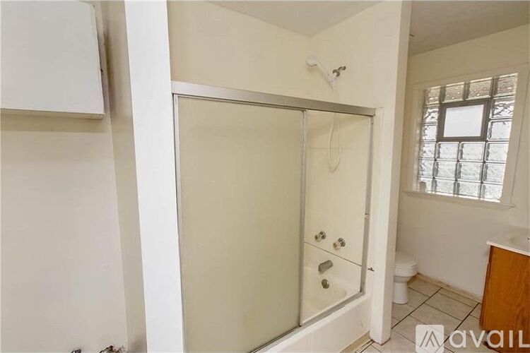 A bathroom with a glass shower door and a window.