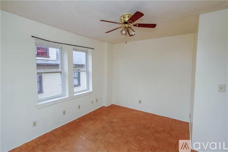 A room with a ceiling fan and two windows.