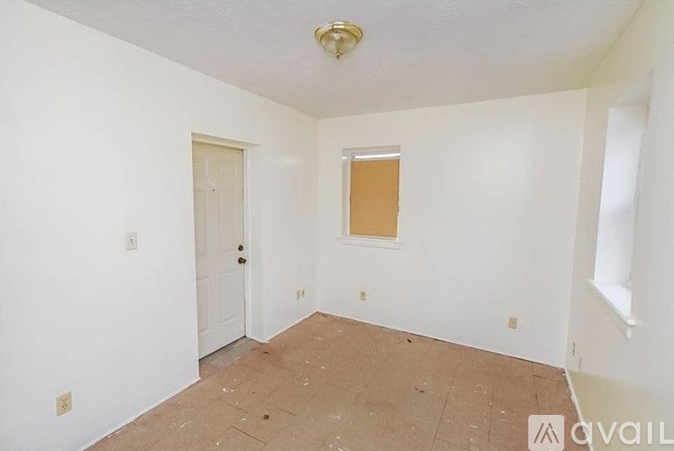 A room with a door, window, and a wooden floor.