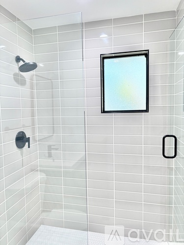 A bathroom with a white tiled shower and a picture frame on the wall.