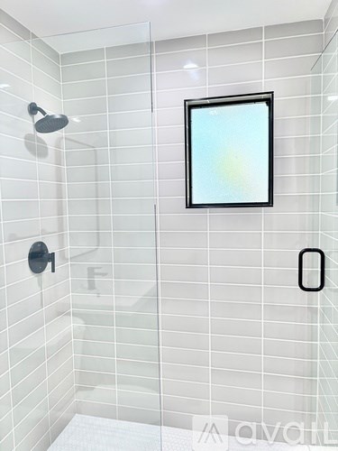 A bathroom with a white tiled shower and a picture frame on the wall.