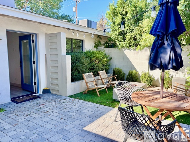 A patio with a table and chairs and a blue umbrella.