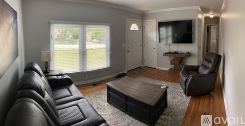 A living room with a black leather couch and a wooden coffee table.