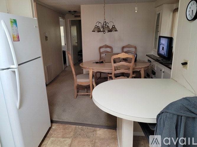 A kitchen with a white fridge and a table with chairs.