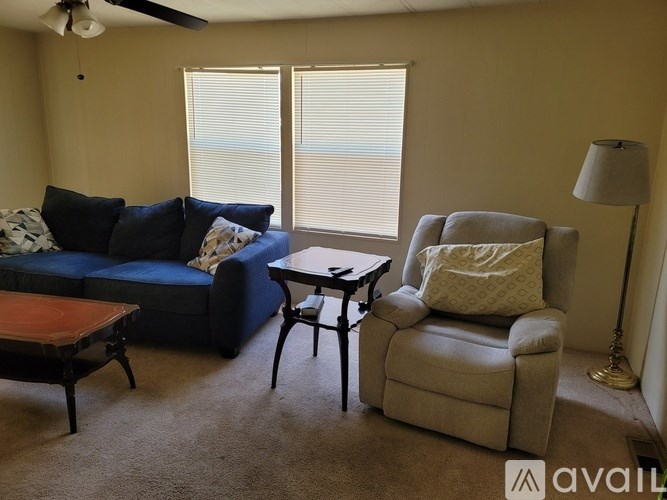 A living room with a blue couch, a grey armchair, and a wooden coffee table.