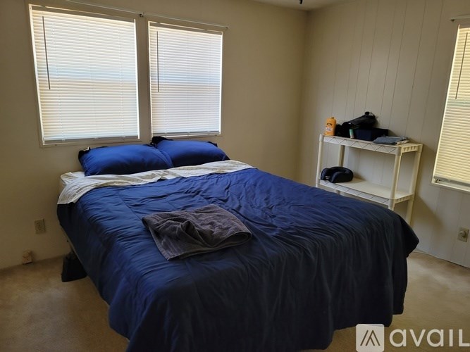 A bed with blue bedding and a white nightstand with a lamp on it.