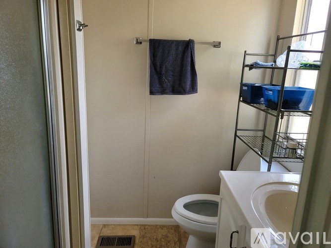A bathroom with a towel hanging on the wall and a toilet with a white lid.