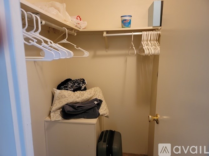 A small closet with a shelf and clothes on it.