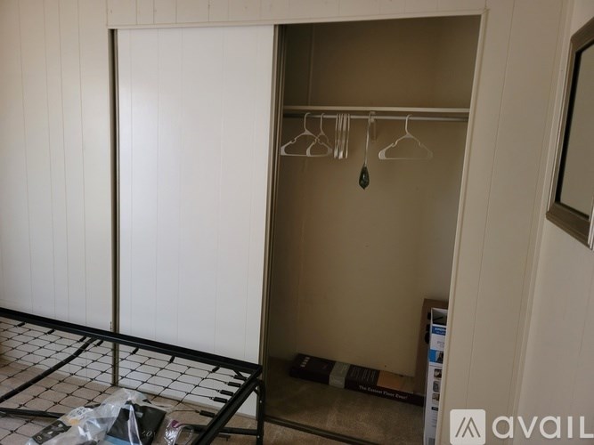 A white closet with a black ironing board and clothes hanging on a rack.