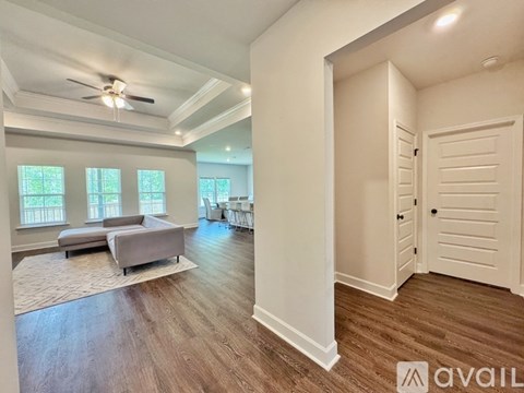 A spacious living room with a grey sofa and a ceiling fan.