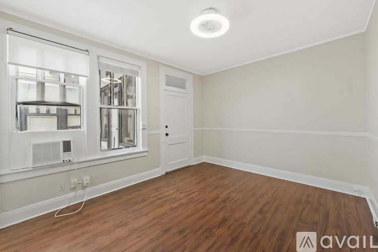 A room with a ceiling fan and two windows.