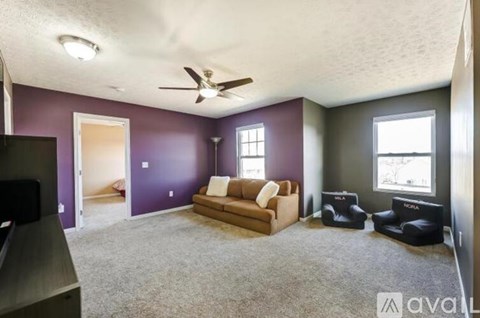A living room with a brown couch and a ceiling fan.