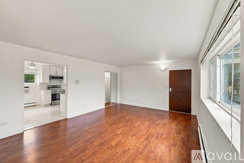 A spacious room with wooden floors and white walls.