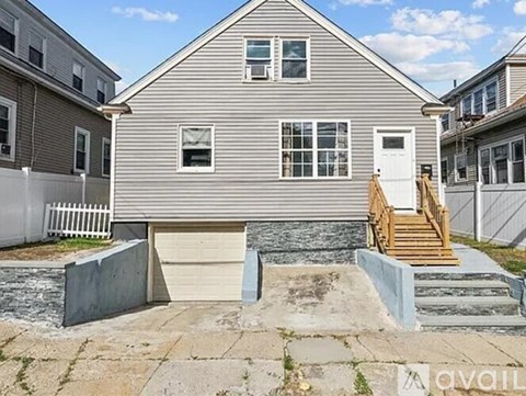 A house with a grey exterior and a white door is for sale.