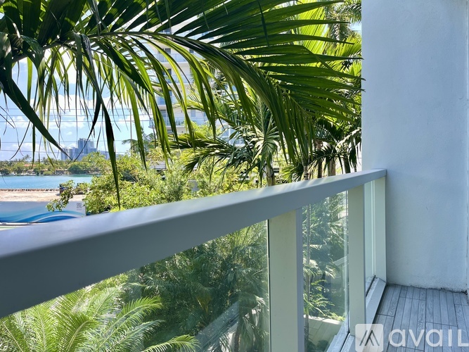 A balcony with a view of a pool and palm trees.