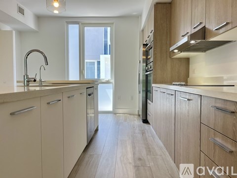 A modern kitchen with wooden cabinets and a stainless steel refrigerator.
