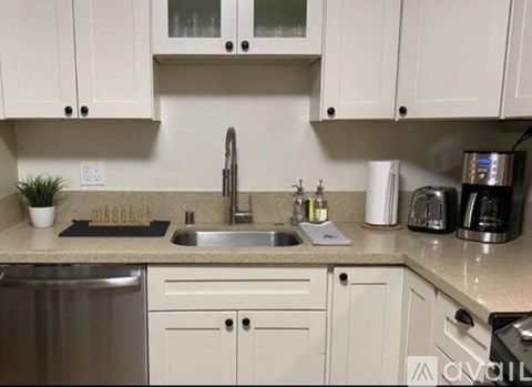 A kitchen with white cabinets and a stainless steel dishwasher.