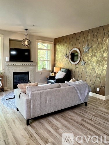 A living room with a grey couch and a fireplace.