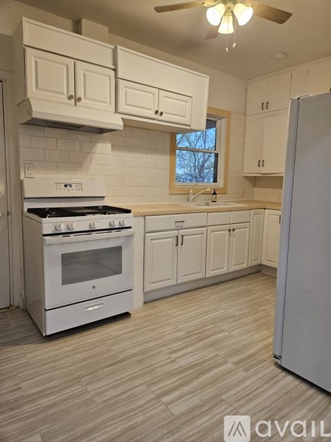 A kitchen with white appliances and cabinets.